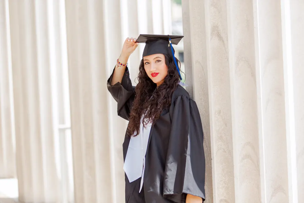A graduate tossing her cap between white columns