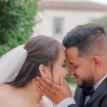 A bride and groom forehead to forehead, her hand on his cheek