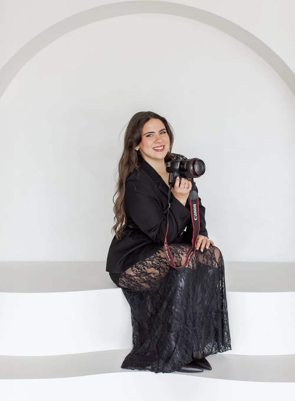 Milena sitting in a white arch with her camera