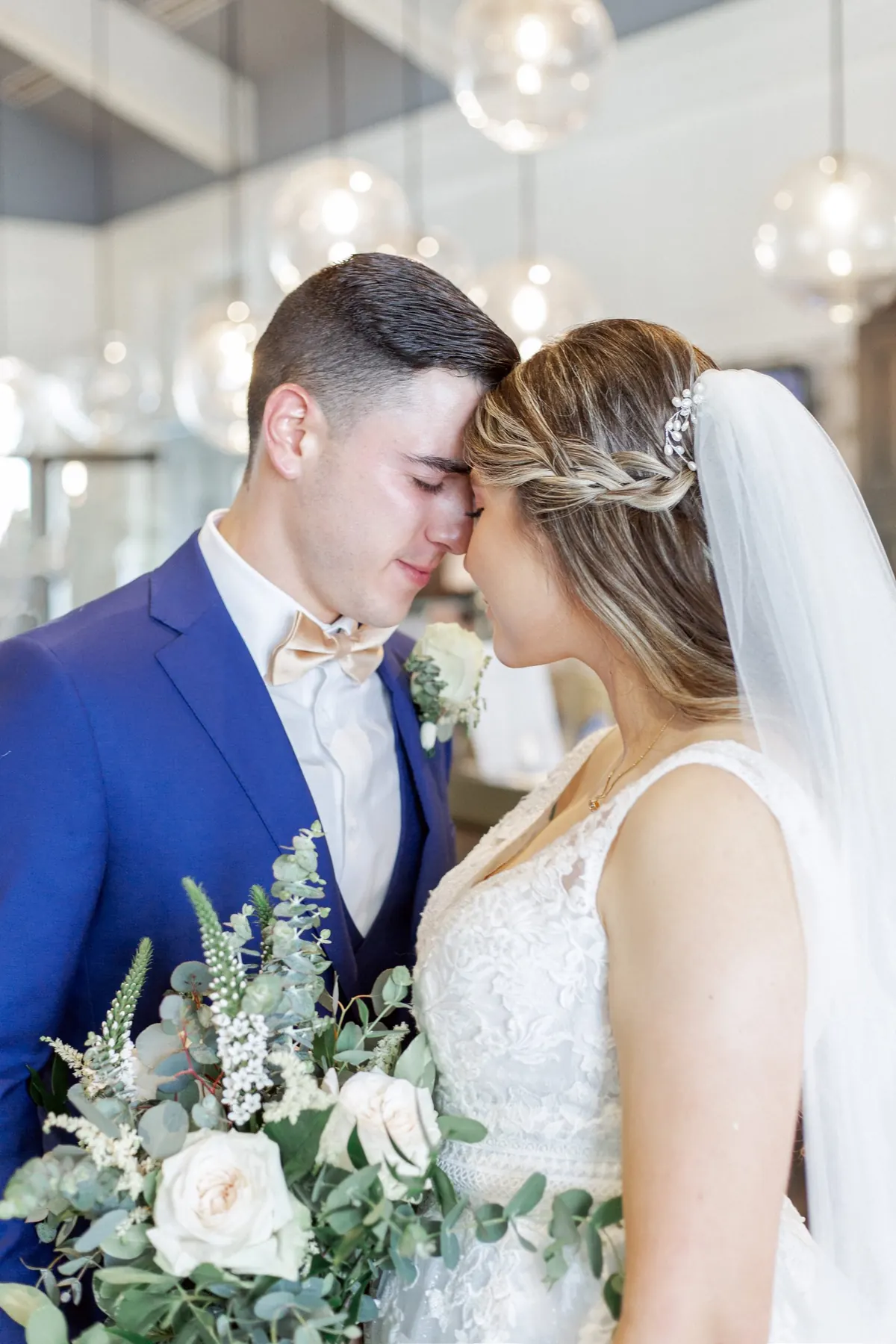 Bride and groom forehead to forehead with a white bouquet